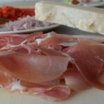 Lonchas finas de jamón con rúcola cubiertas de láminas de parmesano Lonchas finas de jamón con rúcola cubiertas de láminas de parmesano